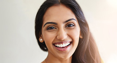 A beautiful model with white teeth smiling at the camera in Clapham Common in London