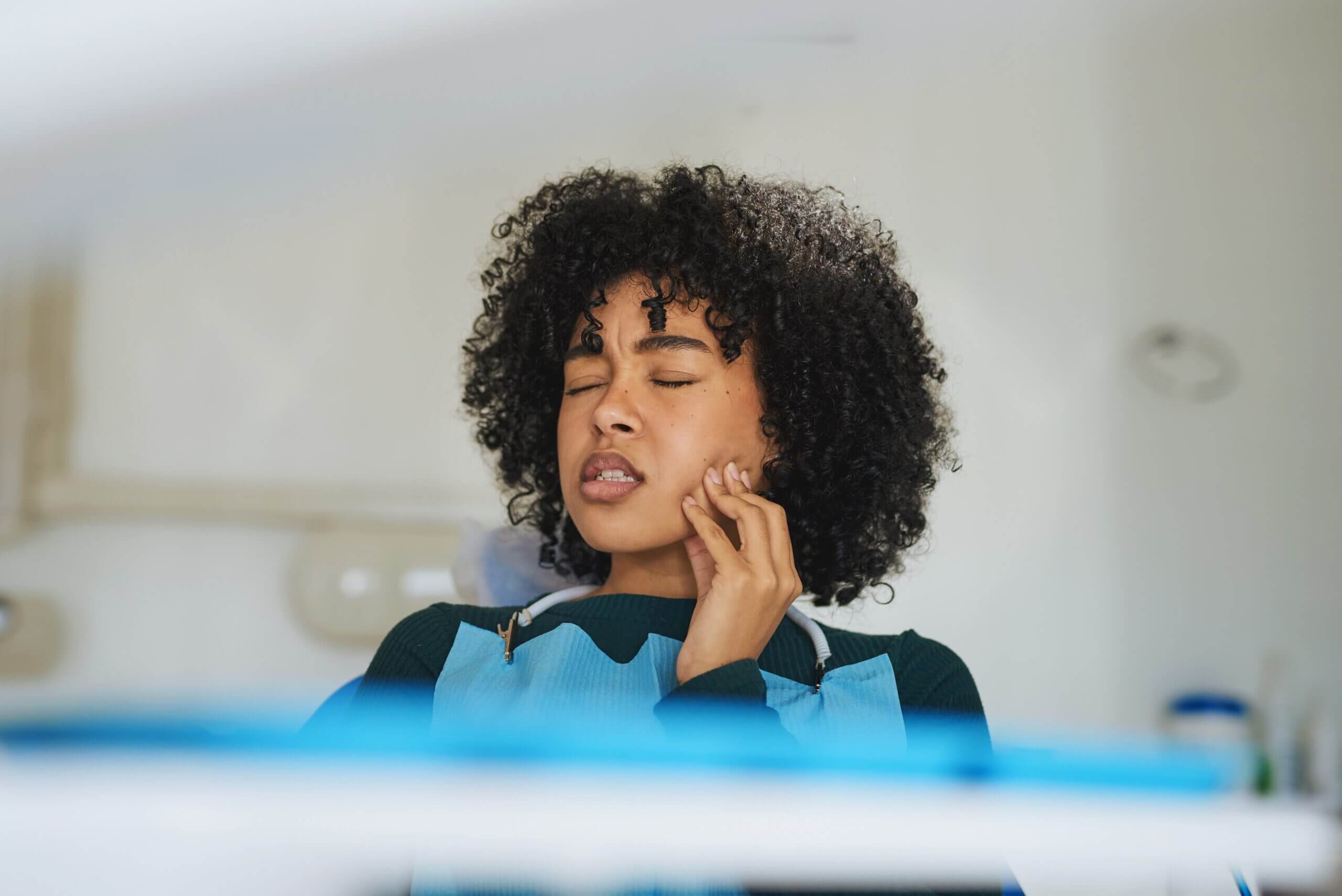 Girl holding the side of her face in need of an dental emergencies appointment